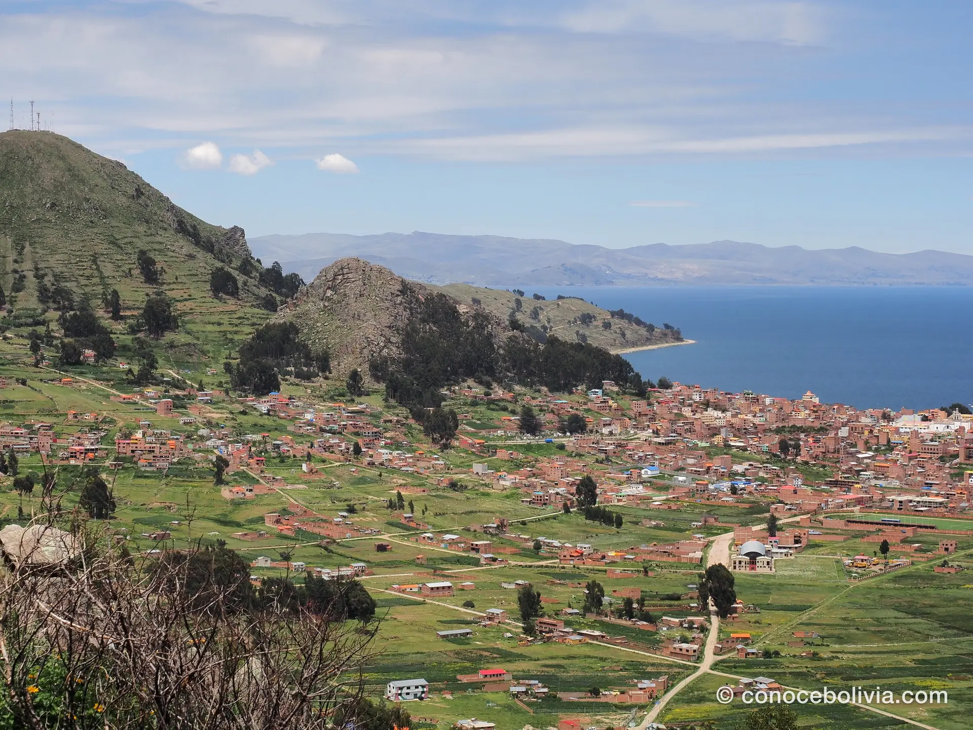 Vista aérea de Copacabana curvándose junto a la orilla del lago, entre dos cerros
