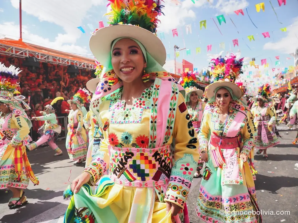 Bailarina sonriente con traje amarillo bordado y sombrero con plumas de colores