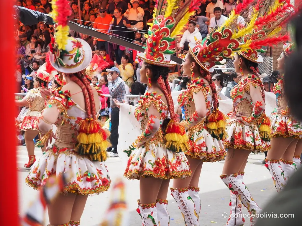 Bailarinas con botas blancas, faldas bordadas y tocados de plumas rojas y amarillas