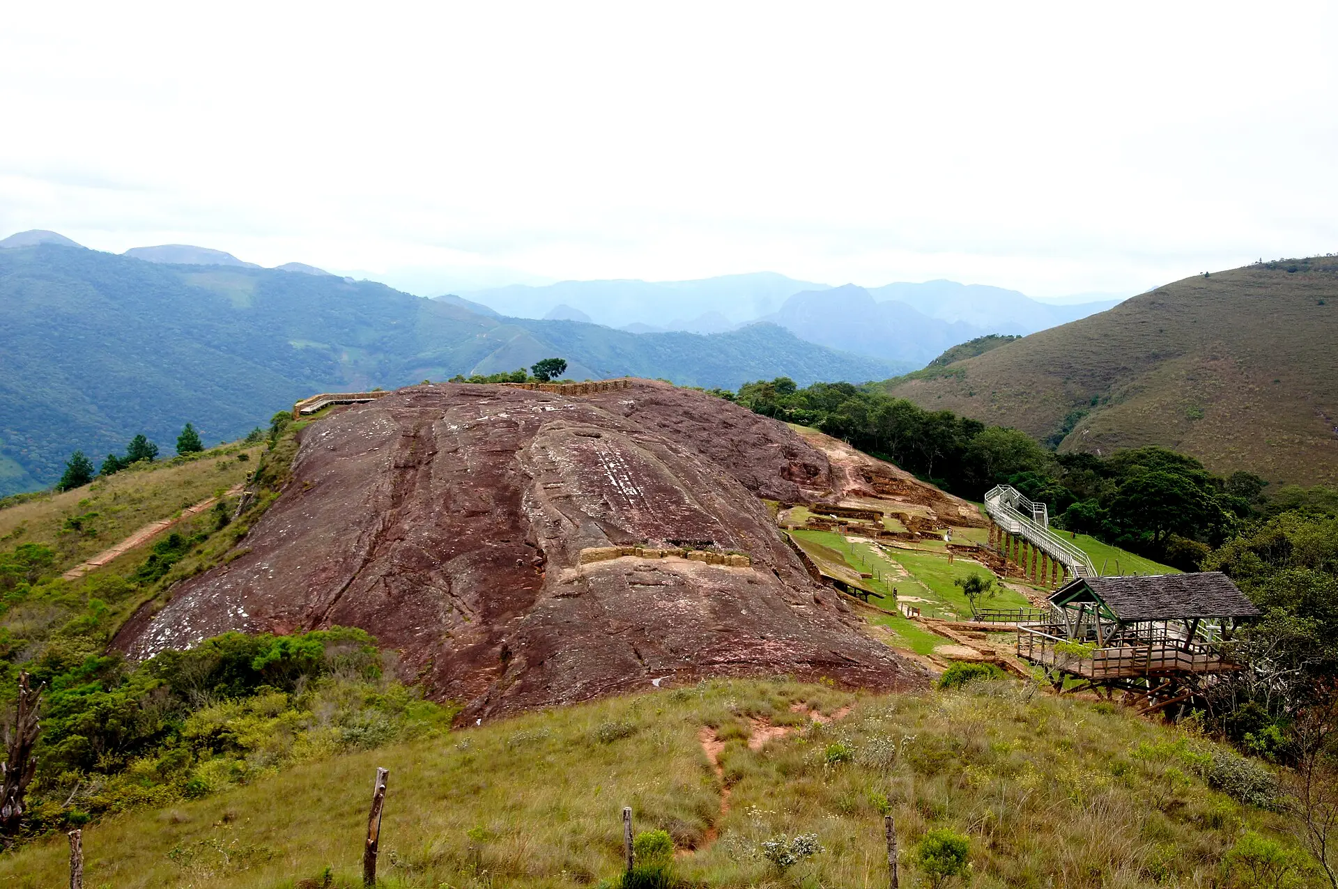 La gran roca rojiza de El Fuerte de Samaipata vista desde el mirador, rodeada de colinas