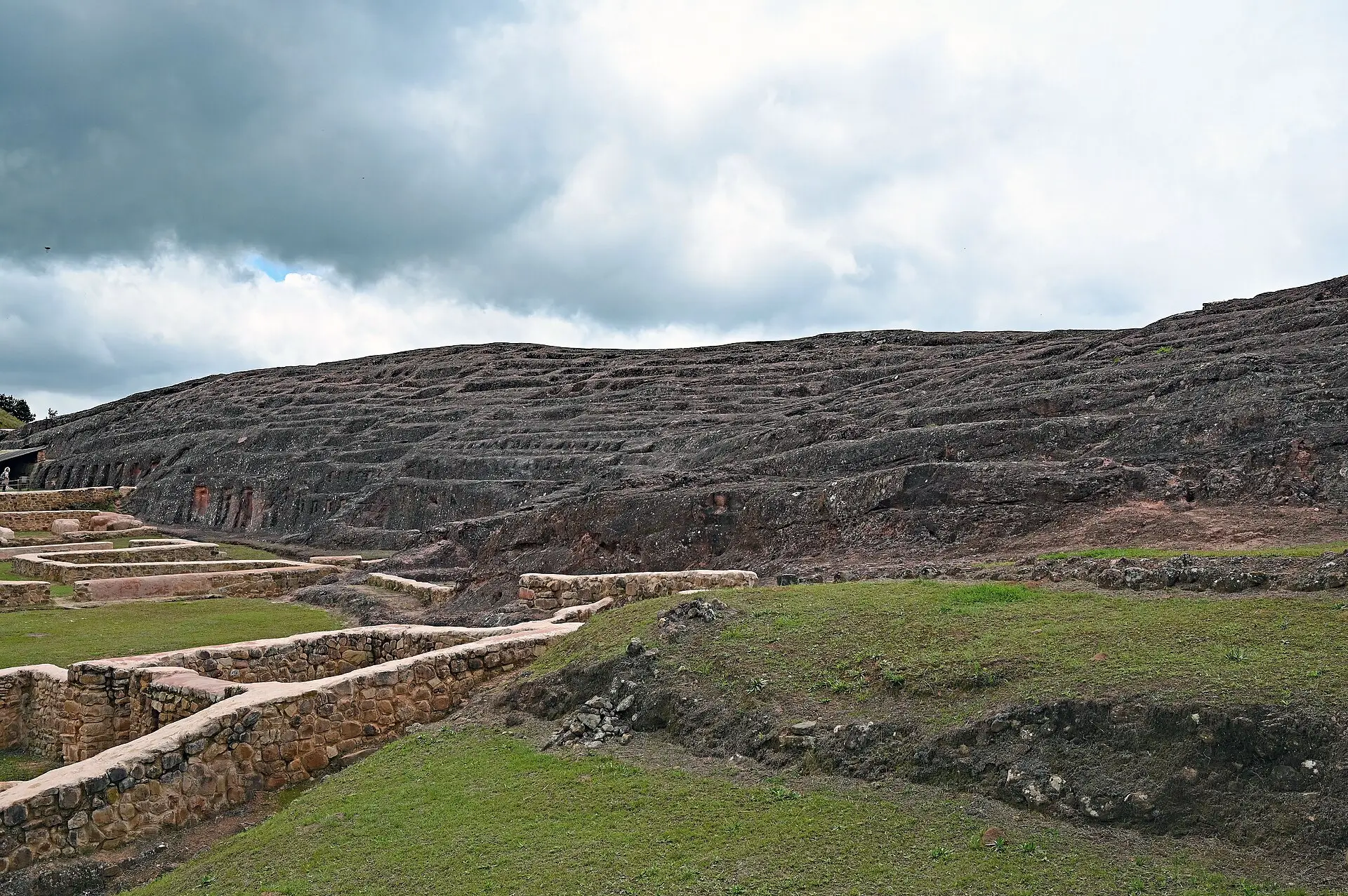 Muros de piedra de antiguos recintos al pie de la roca tallada de El Fuerte