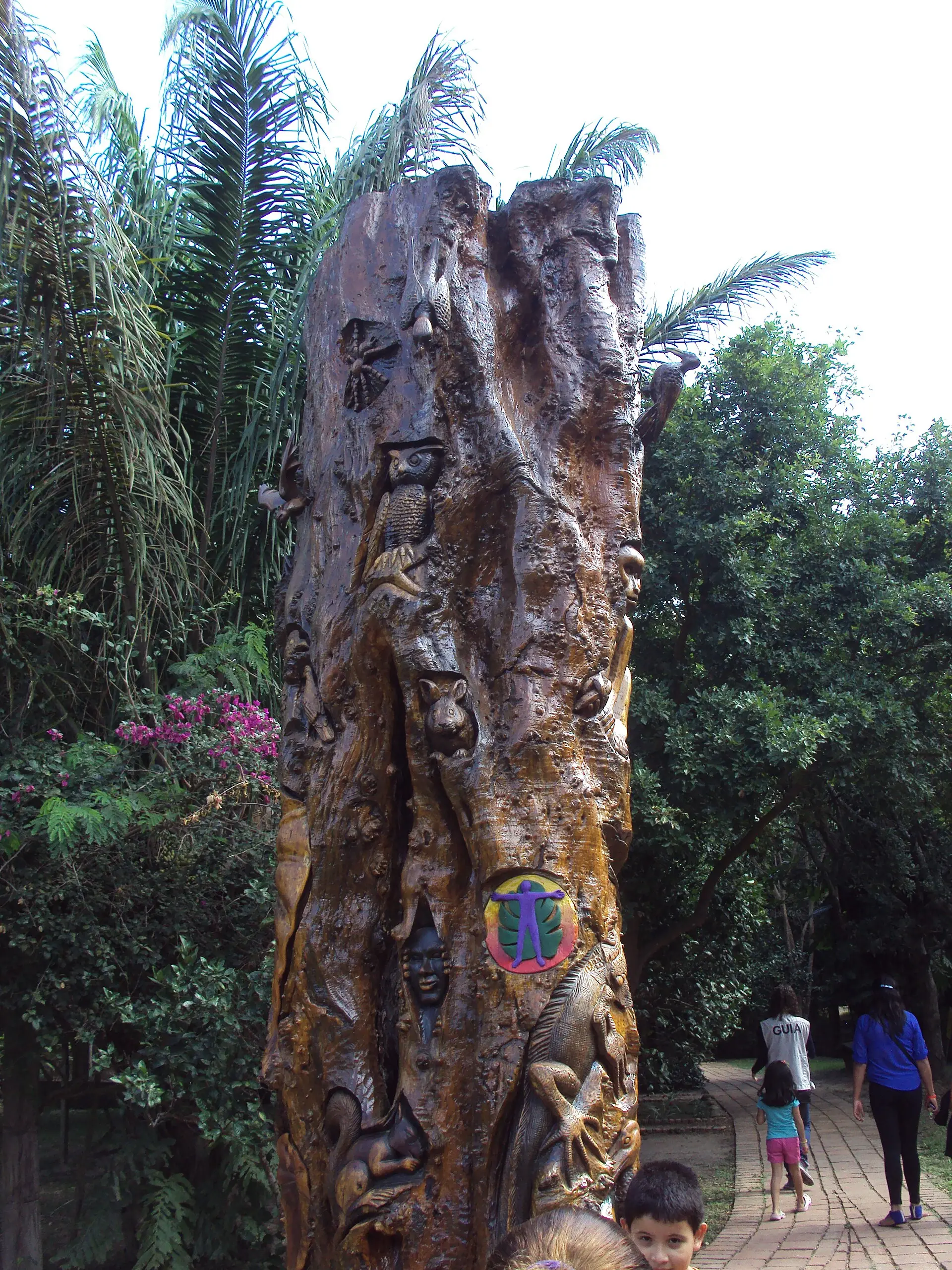 El árbol de la diversidad: tronco tallado con figuras de animales entre palmeras en Güembé