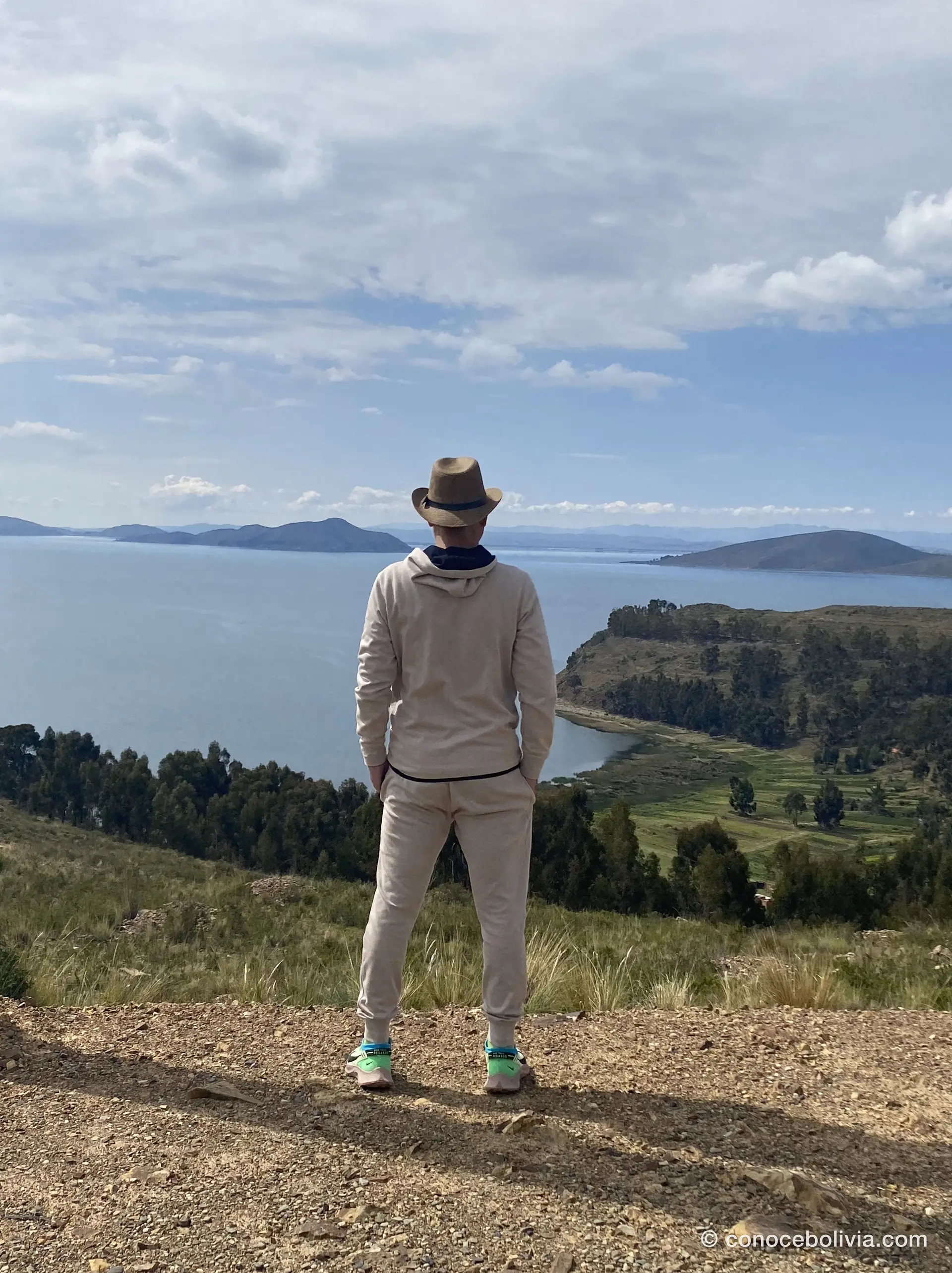 Persona mirando el Lago Titicaca desde un mirador, de espaldas, con islas al fondo