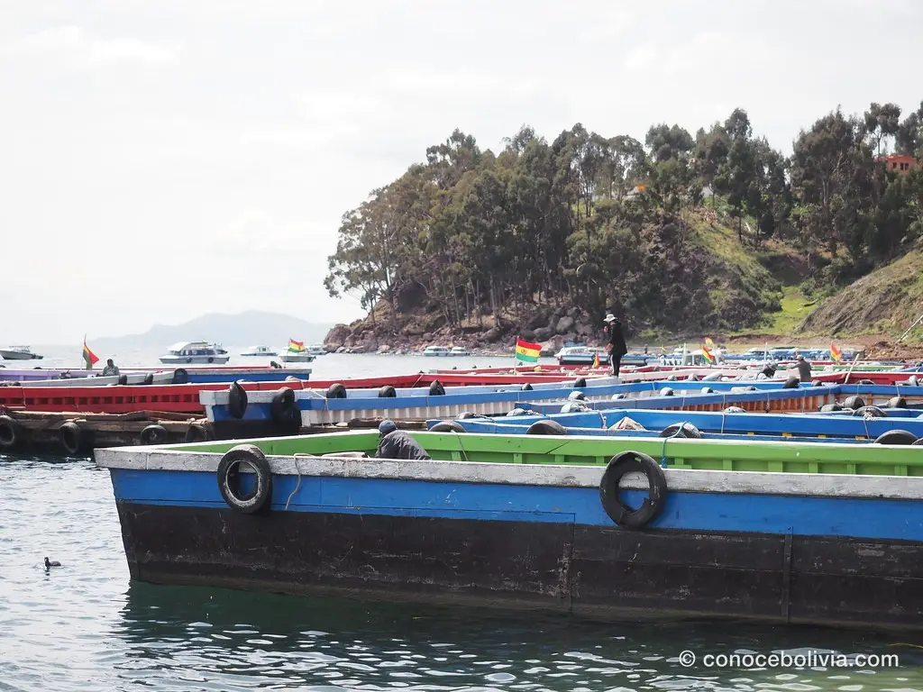 Lanchas de colores atracadas en un pueblo a orillas del Lago Titicaca, con banderas de Bolivia