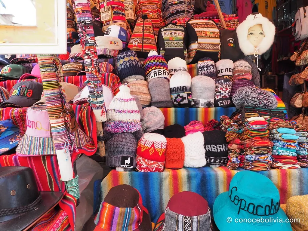 Puesto de mercado con gorros y textiles bordados con el nombre Copacabana