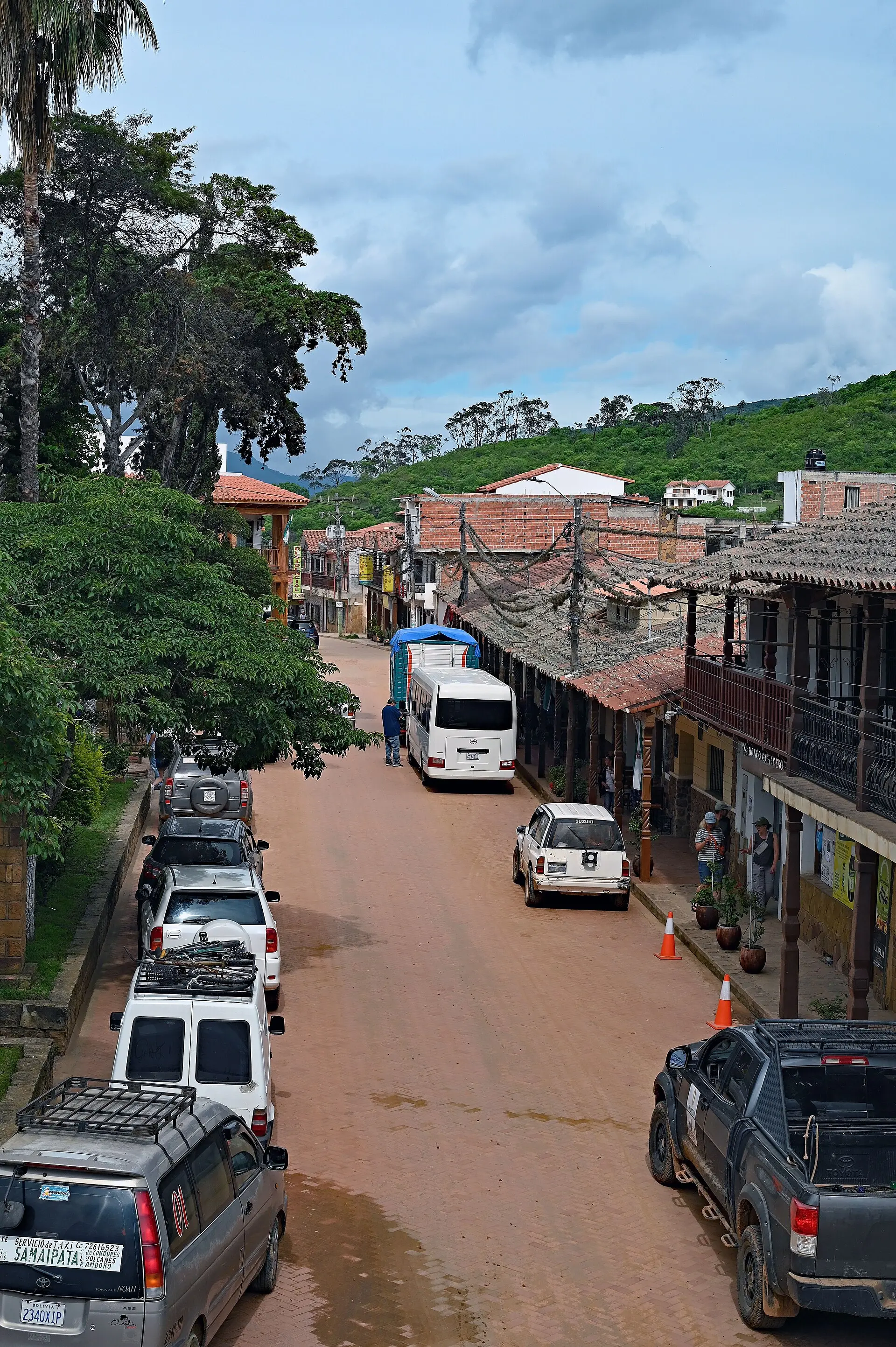Calle del centro de Samaipata con casas de balcones de madera y vehículos aparcados